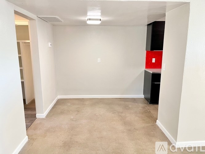 A room with a carpeted floor and a red object on the wall.