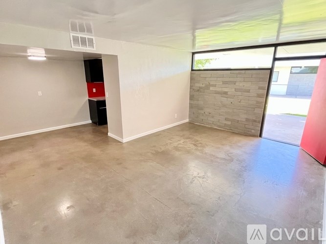 A room with a concrete floor and a red object on the right side.
