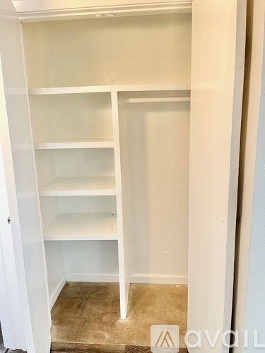 A white shelving unit with four shelves is in a room with a tiled floor.