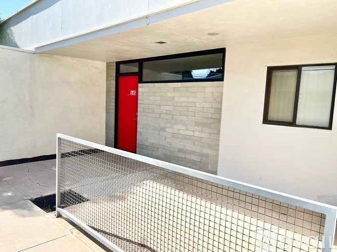 A tennis court is set up outside a building with a red door.