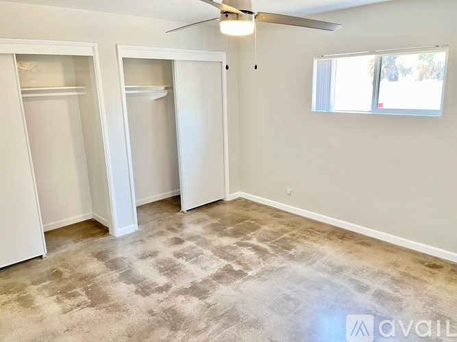 A room with a ceiling fan and two closets.