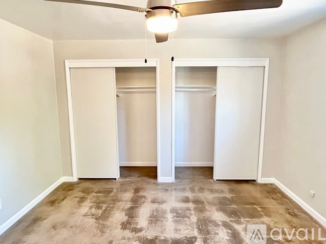 A room with a ceiling fan and two closets.