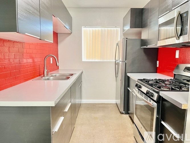 A kitchen with a red tile backsplash and stainless steel appliances.