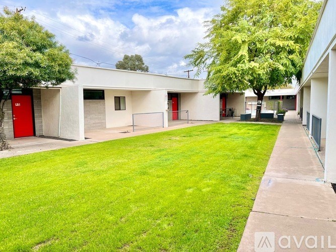 A building with a red door is surrounded by a green lawn.