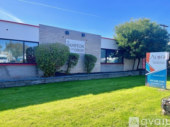 A building with a sign that says "The Hampton on Osborne" and a window with a reflection of a boat.