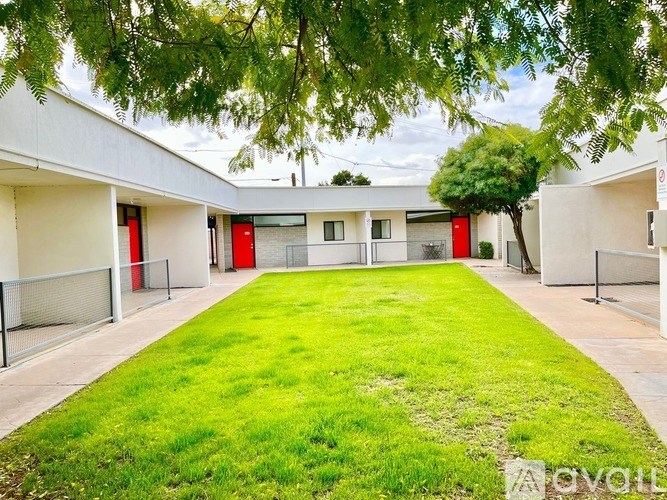 A white building with red doors and a green lawn in front.