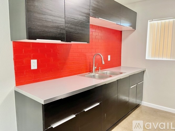 A kitchen with a red tile backsplash and stainless steel appliances.