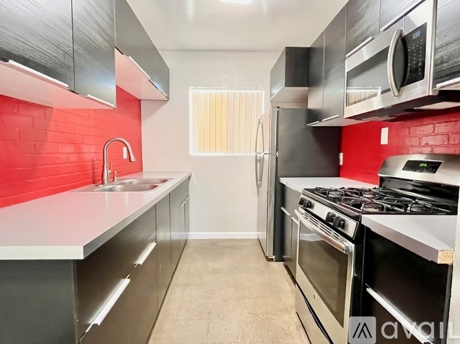 A kitchen with red tiles and stainless steel appliances.