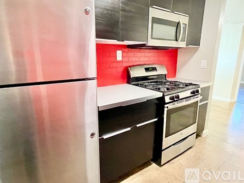 A kitchen with a stainless steel refrigerator and a red backsplash.