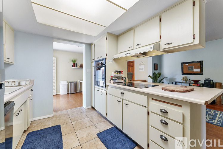 A kitchen with white cabinets and a blue rug on the floor.