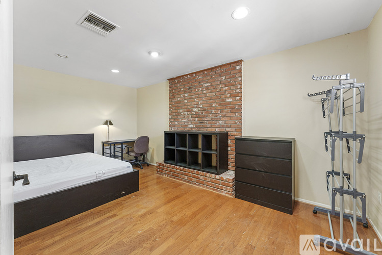 A bedroom with a brick wall and wooden floors.