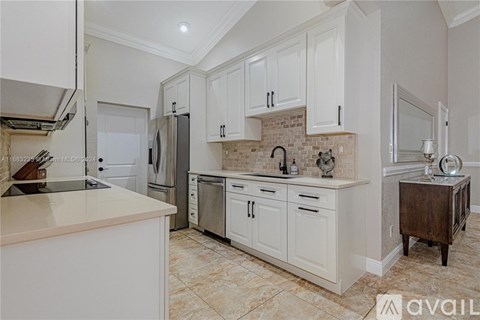 A kitchen with white cabinets and a marble countertop.