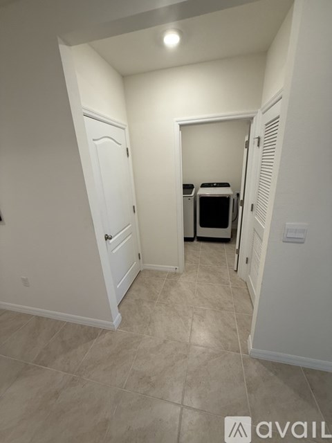 A hallway with a door on the left and a kitchen area on the right.