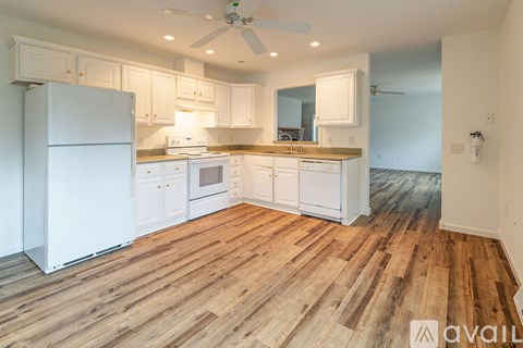 A kitchen with white appliances and wooden floors.