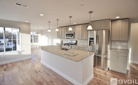 A modern kitchen with a granite countertop and stainless steel appliances.