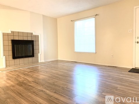 A room with a wooden floor, a window, and a door.