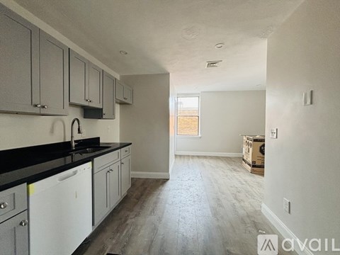 A kitchen with white cabinets and black countertops is available.
