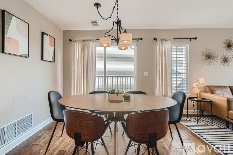 A modern dining room with a round wooden table and chairs.