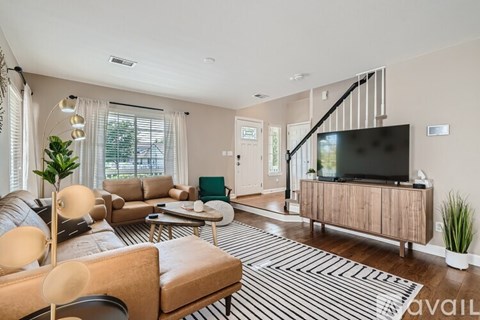 A living room with a striped rug and a brown leather sofa.