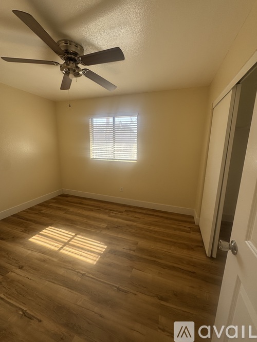 A room with a ceiling fan and wooden flooring.