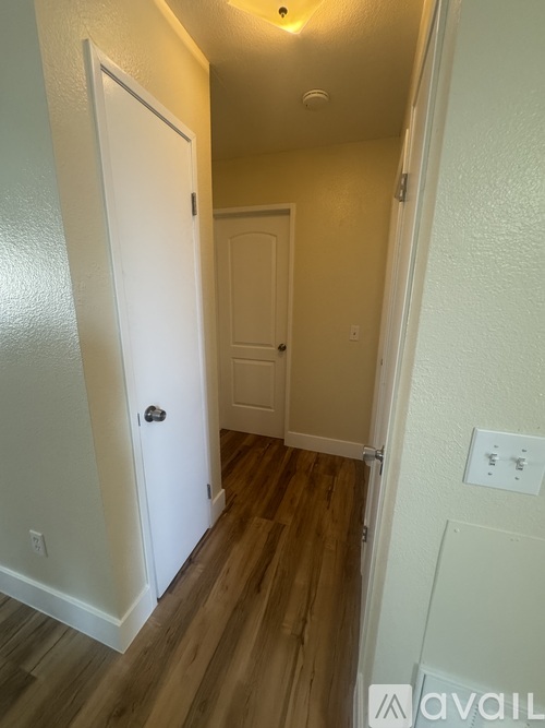 A hallway with a white door and a wooden floor.