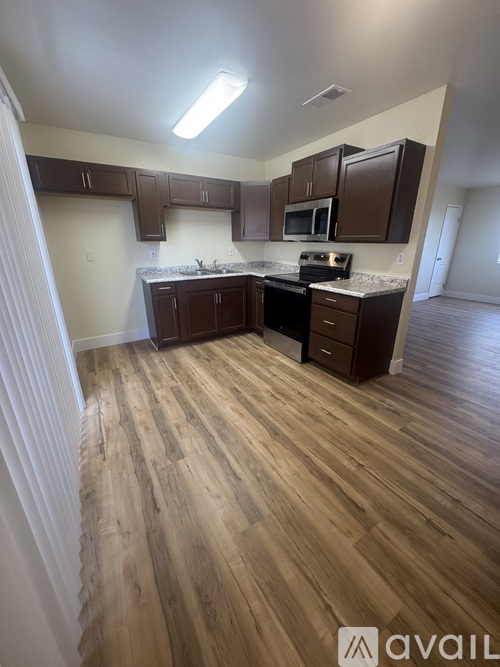 A kitchen with wooden floors and brown cabinets.