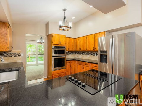 A kitchen with wooden cabinets and a black granite countertop.