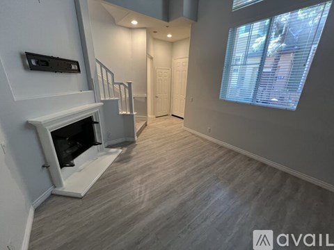 A spacious room with a fireplace and a window with blinds.