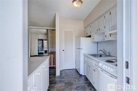 A kitchen with white cabinets and a white fridge.