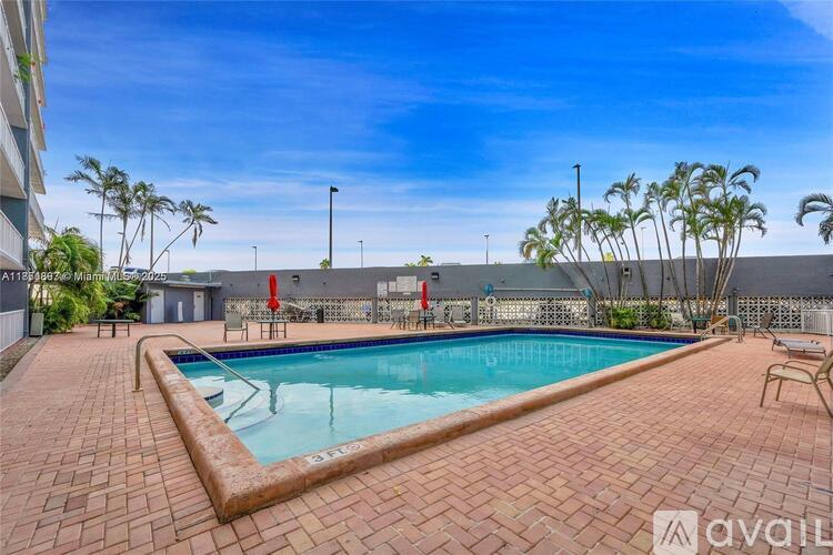 A pool surrounded by a brick patio and palm trees.
