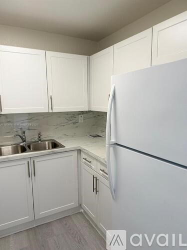 A kitchen with white cabinets and a white fridge.