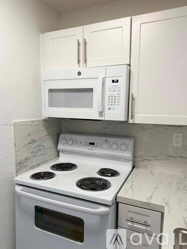 A white microwave oven is mounted above a white stove in a kitchen.