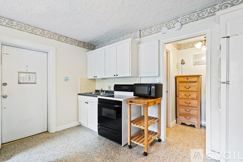 A kitchen with white cabinets and black appliances.