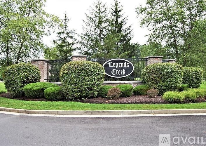 A sign that says Legends Creek in front of a fence and trees.