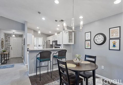 A kitchen with a table and chairs in the foreground and a dining area in the background.