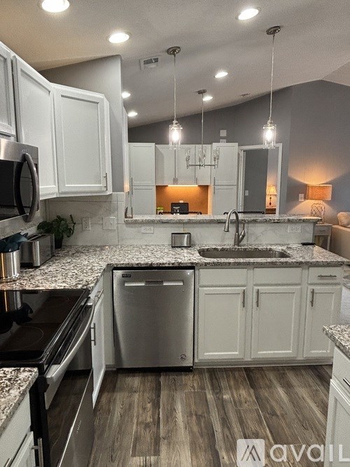 A kitchen with white cabinets and a granite countertop.