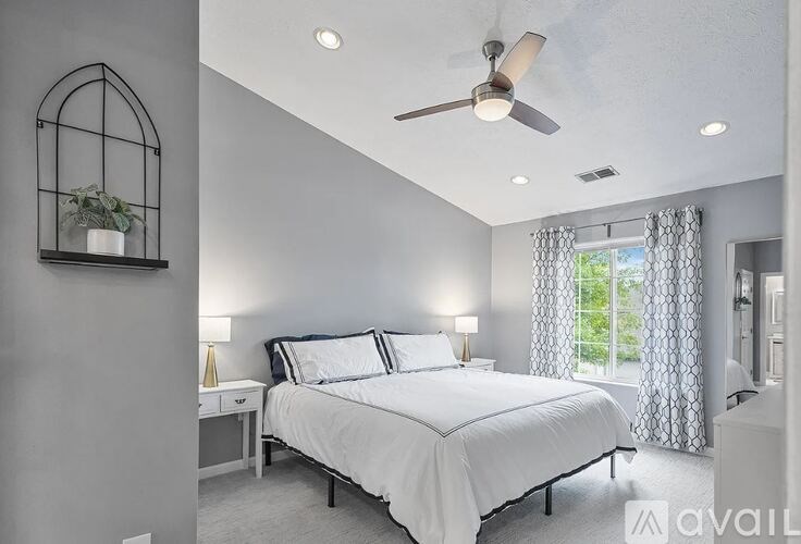 A bedroom with a large bed and a ceiling fan.