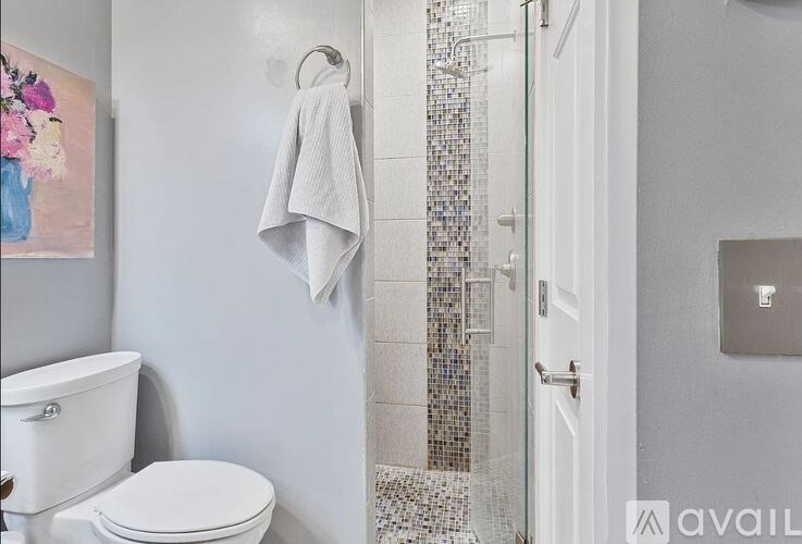 A white toilet sits next to a white towel hanging on a towel ring.