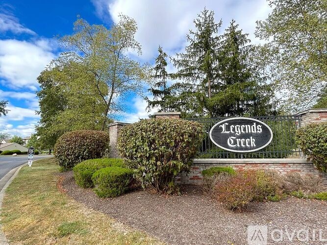 A sign that says Legends Creek in front of some bushes.