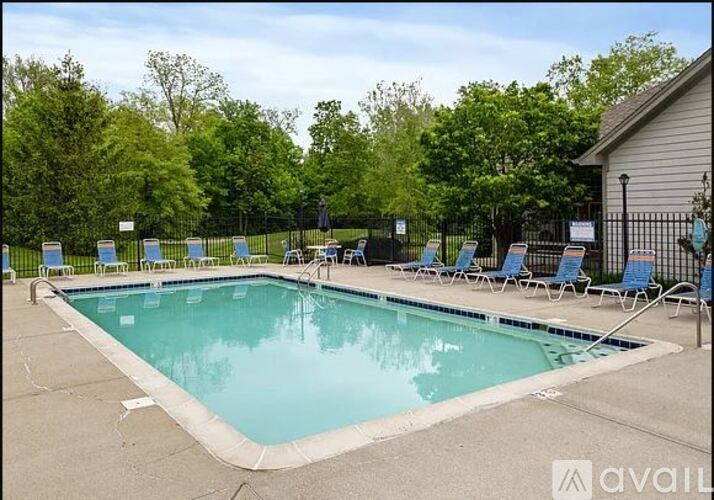 A pool surrounded by trees and chairs.