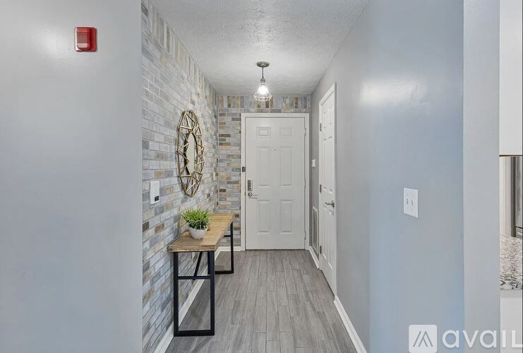 A hallway with a white door, a table with a plant, and a wall with a circular decoration.