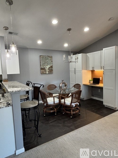 A well-lit, modern living room with a dining area and a kitchen in the background.