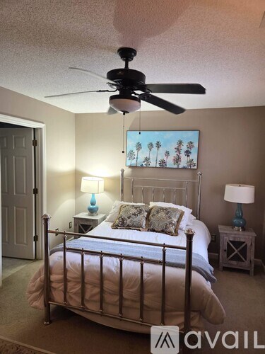 A bedroom with a bed, two lamps, and a ceiling fan.