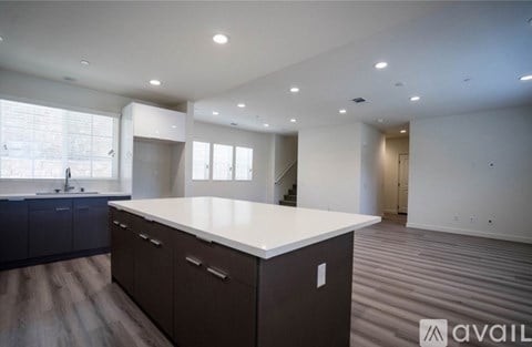 A spacious kitchen with dark brown cabinets and a white countertop.