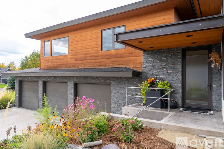 A modern house with a wooden exterior and a stone wall.