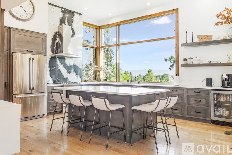 A kitchen with a large island and a view of the trees outside the window.