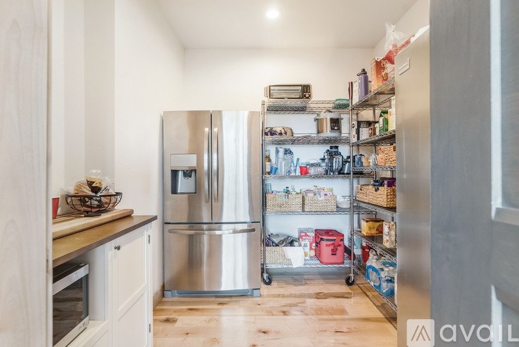 A kitchen with a stainless steel refrigerator and wooden flooring.