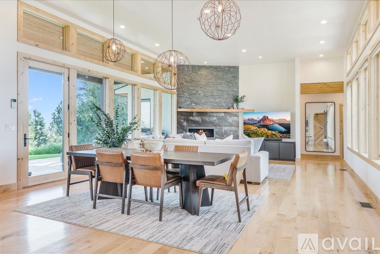 A modern dining room with a stone fireplace and wooden furniture.