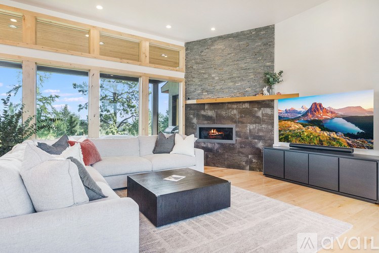 A modern living room with a stone fireplace and a large flat screen TV.