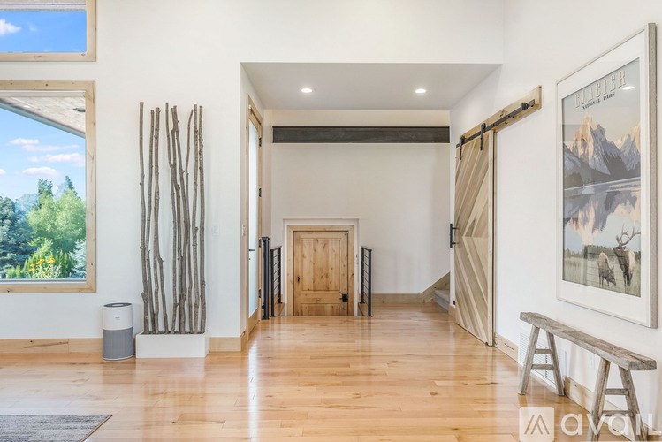 A room with a wooden floor and a large window with a view of trees and sky.